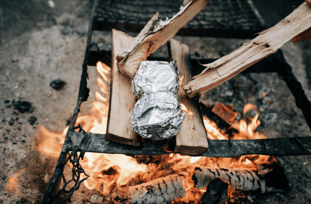 Campfire cooking foil wrapped dinner cooking around a fire