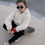 kid in fur jacket sitting on skateboard