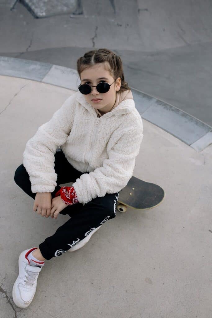 kid in fur jacket sitting on skateboard