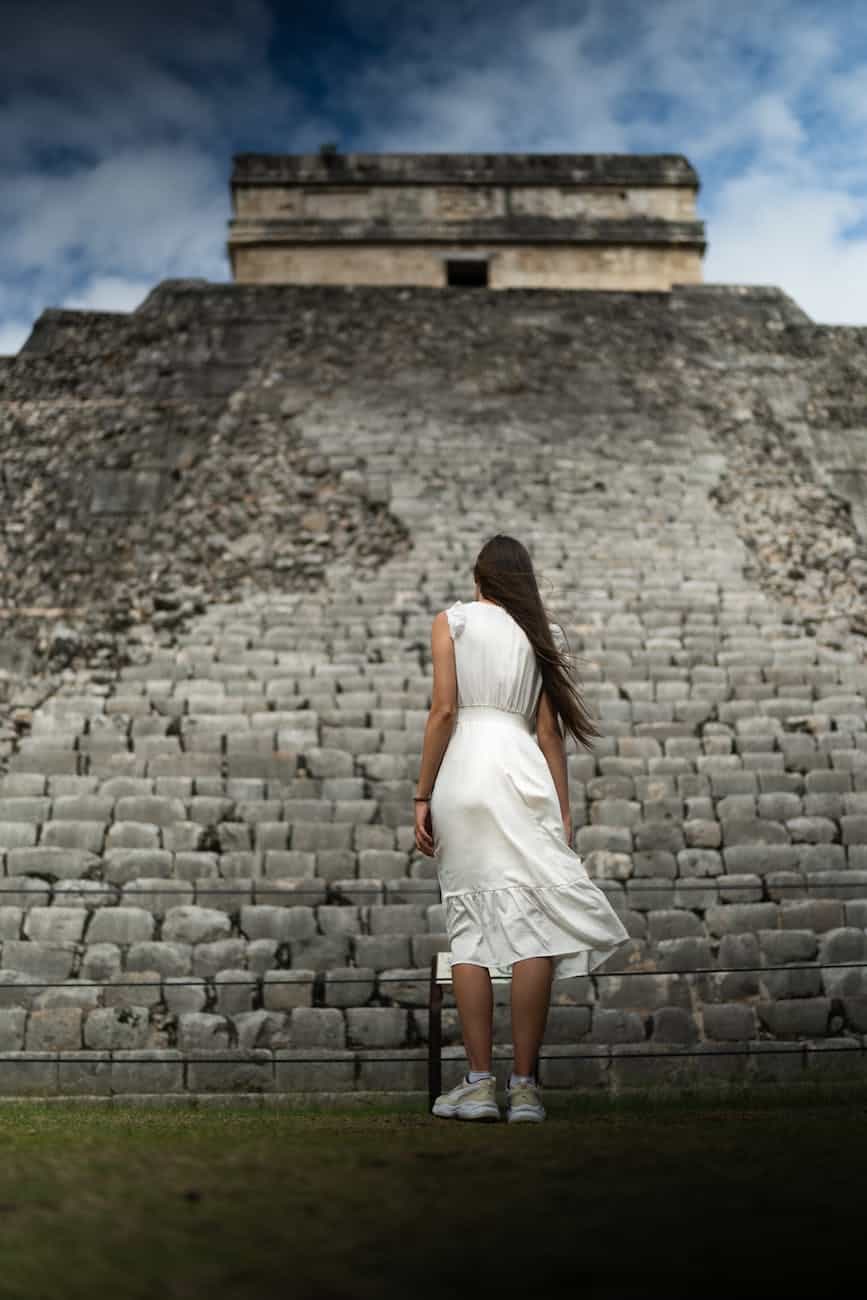 woman in white dress standing in front of a pyramid
