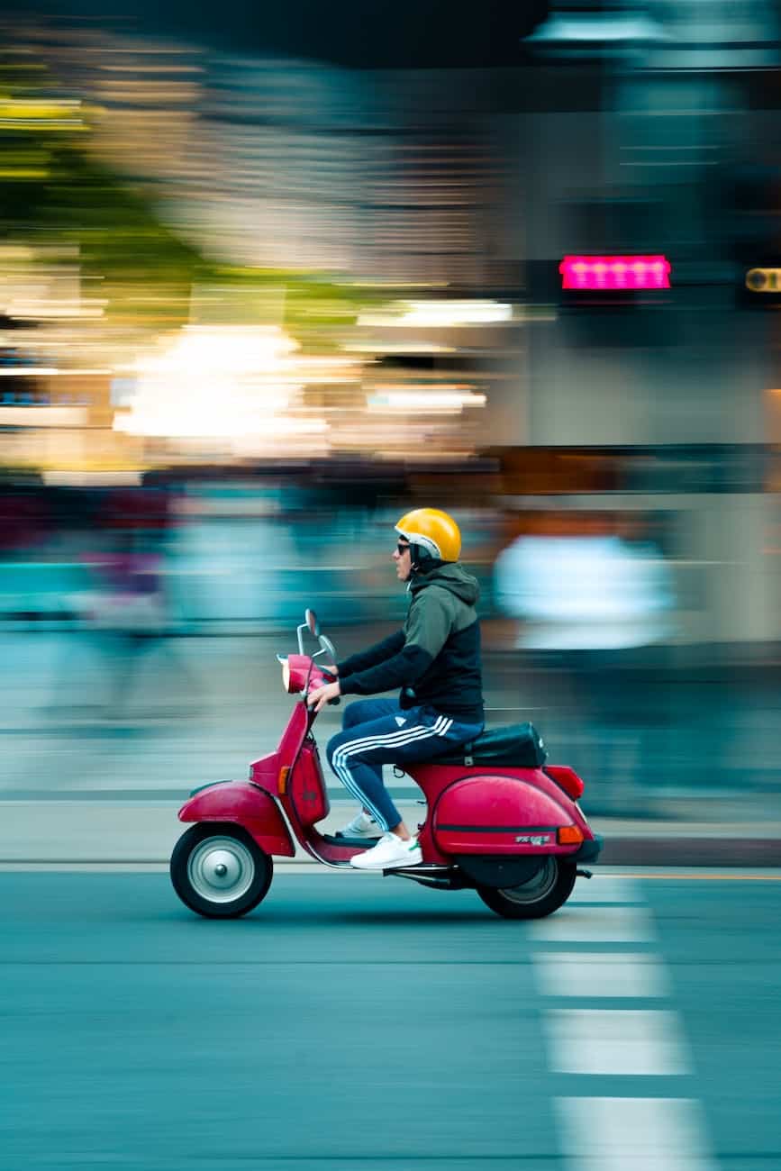 photo of man riding red motor scooter